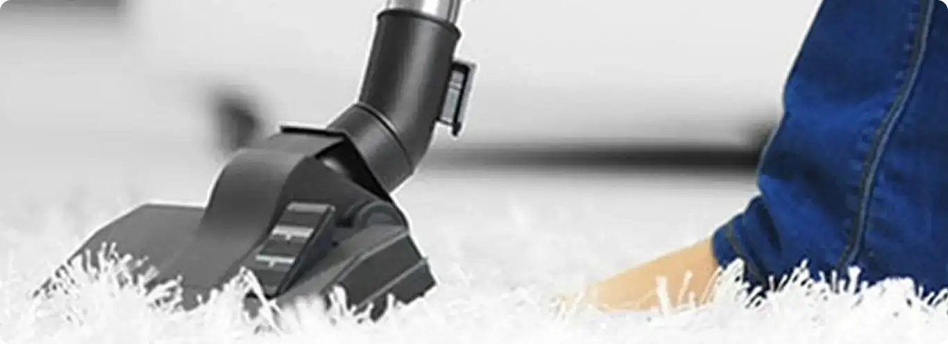 Close-up of a professional vacuuming a white carpet in Eastchester.