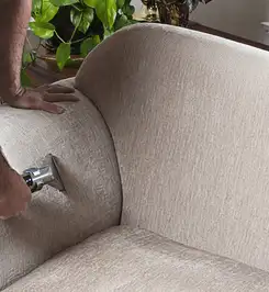Professional upholstery cleaner deep-cleaning a fabric sofa with a handheld extraction tool and hose Yonkers, NY.